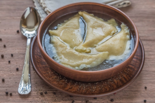 Ceramic bowl of chicken kreplach in soup